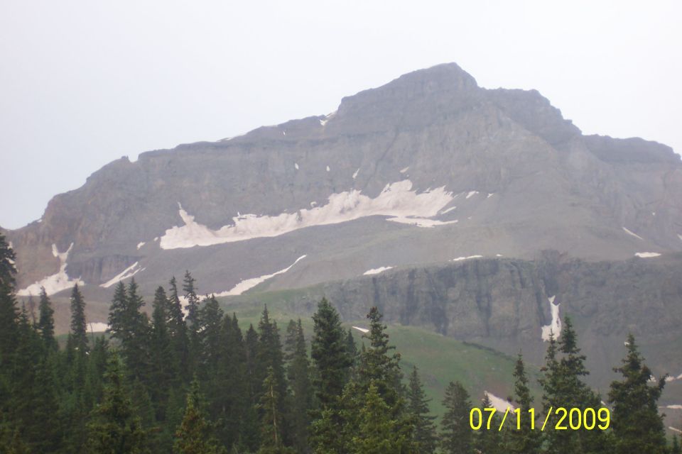Mountain landscape with snow patches and pine trees, overlayed with "SUPER2009TORS" and "www.supermotors.net"