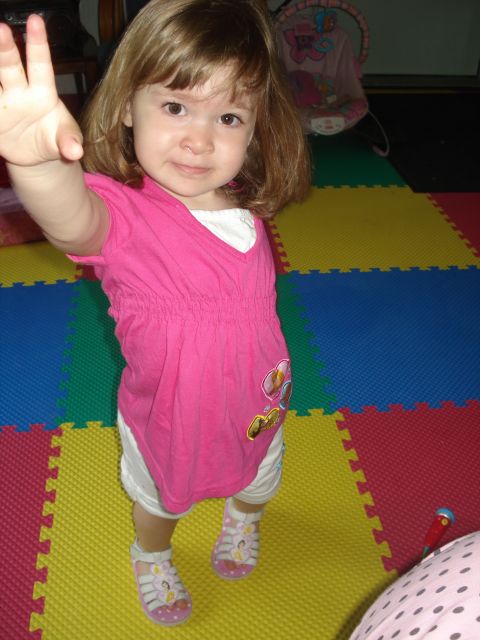 2000 Ford Crown Victoria - A young child stands on a multi-colored play mat, holding up her hand.