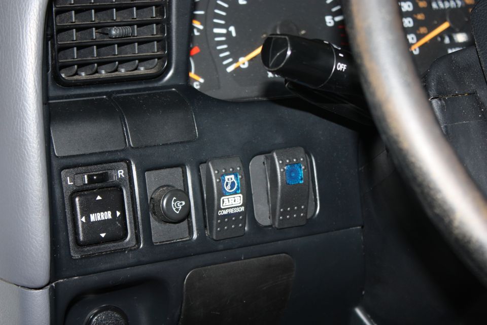 Dashboard interior showing mirror controls, ARB compressor switch, and another auxiliary switch