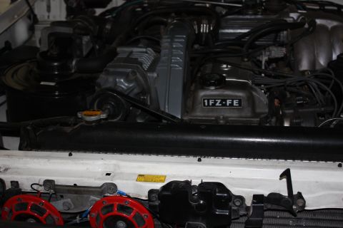 1986 Ford Bronco - Close-up view of an engine bay, showing the 1FZ-FE engine and red aftermarket horns.