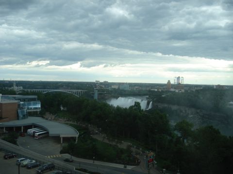 2000 Ford Crown Victoria - A wide view of Niagara Falls with a bridge and city in the background under a cloudy sky.