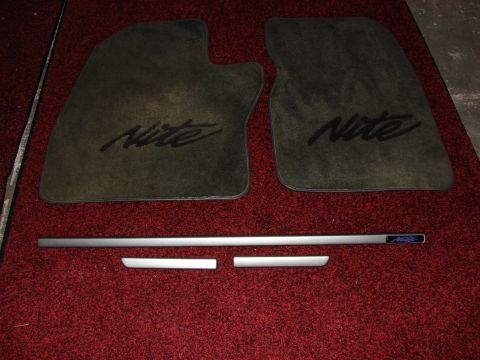 1984 Ford F-250 - Car floor mats and trim pieces with 'Nite' branding are shown on a red carpeted surface.