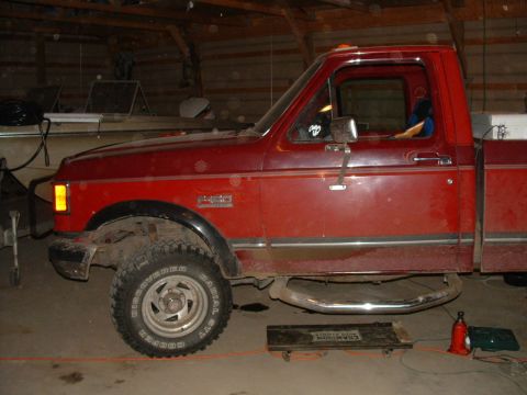 1988 Ford F-150 - A red pickup truck is parked inside a garage, with a boat visible in the background.