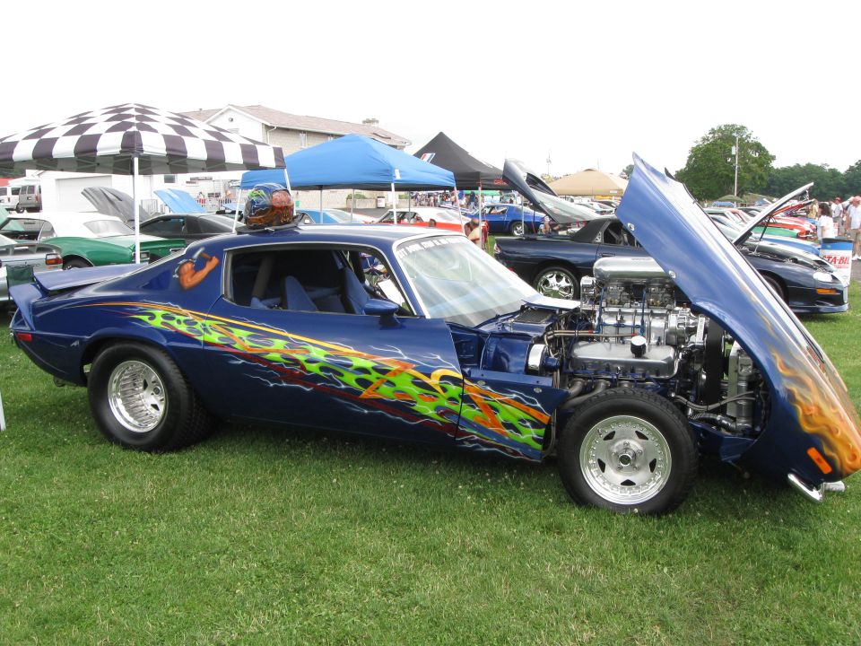 Blue muscle car with flame decals and exposed engine, hood open