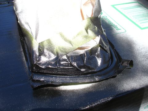 1993 Ford Taurus - A close-up of a masked object, likely a car part, undergoing a spray paint application.