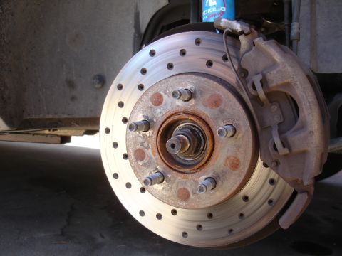 1990 Ford Taurus - A close-up view of a vehicle's front brake assembly, showing the rotor and caliper.