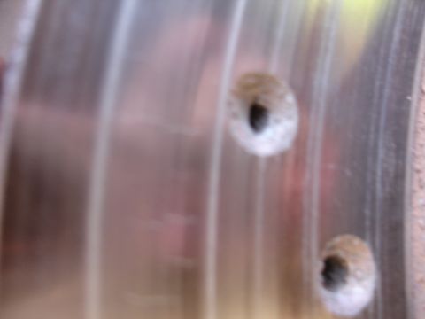 1990 Ford Taurus - A close-up view of a brake caliper, showing two bolt holes. The registry information for this part is not verifiable from the image.
