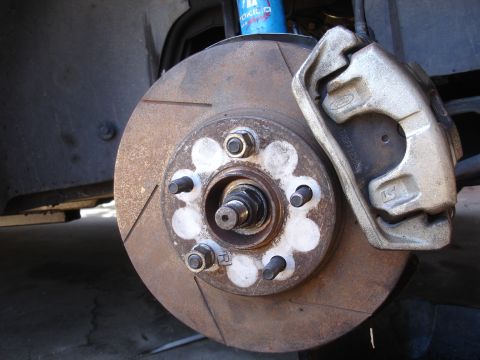1990 Ford Taurus - Close-up of a vehicle's front brake assembly, a rotor and caliper with a Ford emblem.