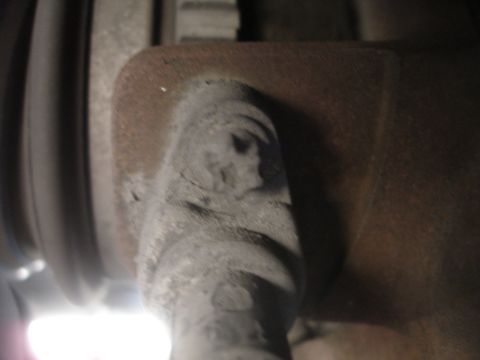 1990 Ford Taurus - A close-up view of a vehicle's brake caliper bracket, showing rust and a bolt head.