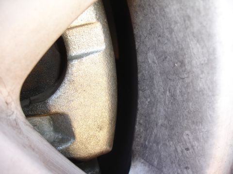 1990 Ford Taurus - Detail of a brake caliper and wheel rim, likely from a vehicle's front end.