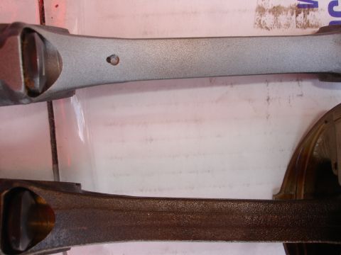 1992 Ford Taurus - Comparison of two engine connecting rods, one appears to be cleaned or new, the other shows signs of rust.
