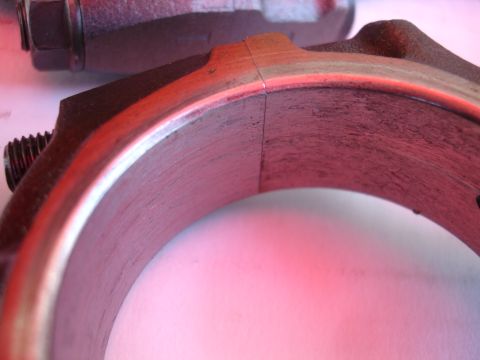 1992 Ford Taurus - Close-up of a worn engine connecting rod bearing, showing signs of damage and a distinct seam.