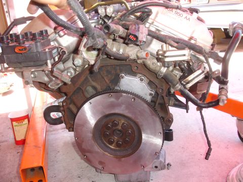 1992 Ford Taurus - Engine assembly on an orange stand, showing flywheel and distributor cap.