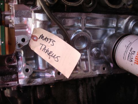 1992 Ford Taurus - A close-up view of an engine block with a handwritten tag and an oil filter attached.