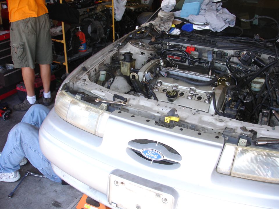 Silver 1992 Ford Taurus engine bay with engine exposed and mechanics working