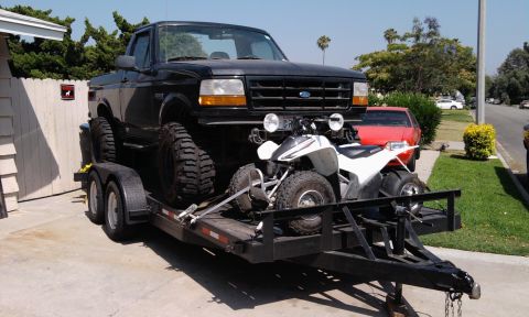1995 Ford Bronco - A black 1995 Ford F-Series truck is loaded onto a trailer with a white ATV.