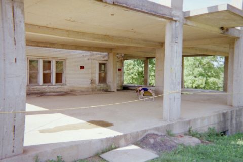 1976 Jeep CJ5 - A person relaxes on a chair within an unfinished concrete structure, with trees visible in the background.