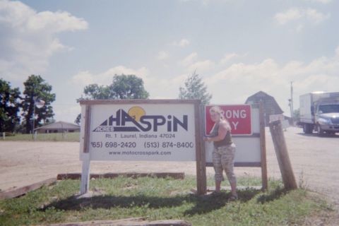 1976 Jeep CJ5 - A person stands by a sign for Haspin Acres, with a truck visible in the distance.