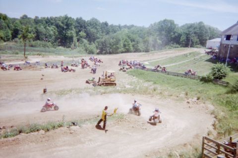 1976 Jeep CJ5 - ATV race in progress on a dirt track with a bulldozer and spectators present.