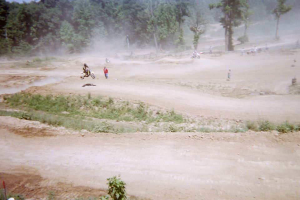Motocross rider jumps a dirt hill with spectators watching