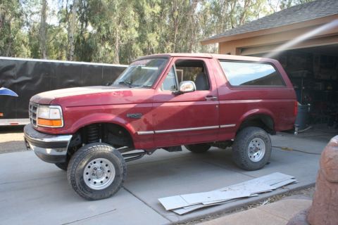 1989 Ford Bronco - This red Ford Bronco features a lifted suspension and aftermarket wheels.