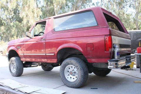 1989 Ford Bronco - Rear view of a red 1989 Ford Bronco with a lifted suspension and custom bumper.