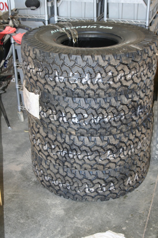 Stack of four All-Terrain T/A tires with white markings on the sidewalls