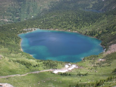 1974 Ford Ranchero - A scenic view of a deep blue mountain lake with turquoise shallows, bordered by dense evergreen forests.