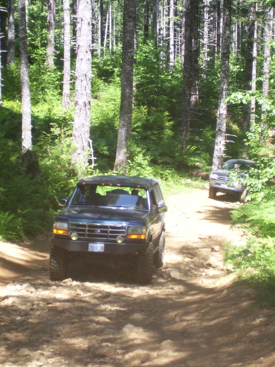 Dark blue SUV with off-road tires on a rocky dirt path, front view
