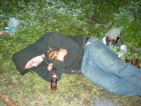 1974 Ford Ranchero - A person sleeps outdoors next to a bottle of alcohol, with white debris scattered on the grass.
