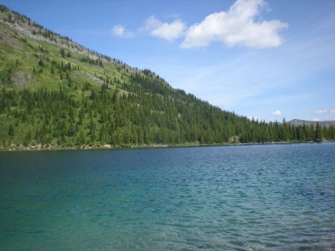 1974 Ford Ranchero - A scenic view of a clear blue lake with a forested mountain slope under a bright sky.