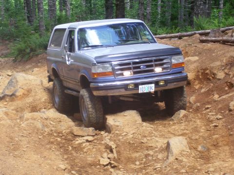 1991 Ford Bronco - Ford Bronco tackling a challenging rocky path in a wooded area.