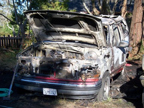 1977 Ford F-150 - A severely damaged truck, likely a Ford F-150, sits with its hood open after a fire, showing extensive burn damage.