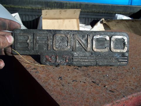1977 Ford F-150 - A close-up of a weathered Bronco XLT emblem, showing significant wear and tear.