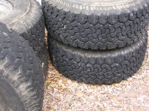 1990 Ford Bronco - Several worn tires are stacked on the ground, with a watermark for SuperMotors.net visible.