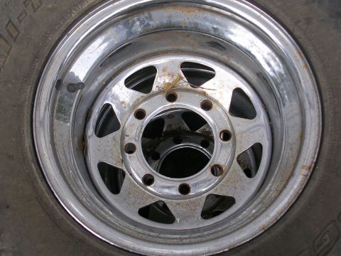 1990 Ford Bronco - Close-up of a chrome wheel and tire, with visible rust and a watermark from Supermotors.net.