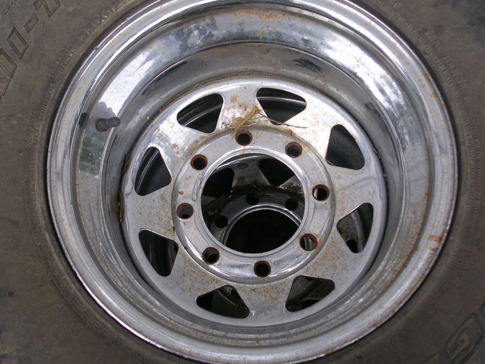 Chrome wheel with tire, showing rust spots and a Supermotors.net watermark