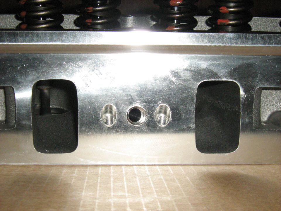 Close-up of an engine cylinder head showing valve springs and bolt holes
