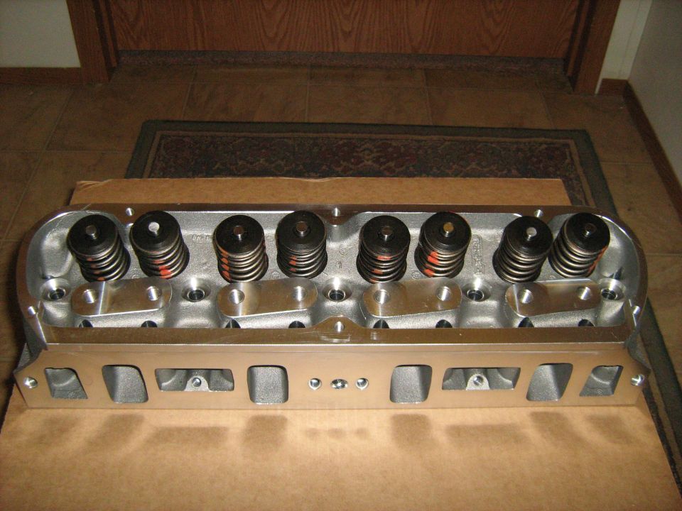 Aluminum engine cylinder head with valve springs and retainers, on a cardboard surface
