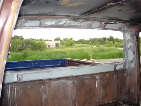 1979 Ford F-250 - View from inside a 1979 Ford F-250 cab, showing the truck bed and a field beyond.