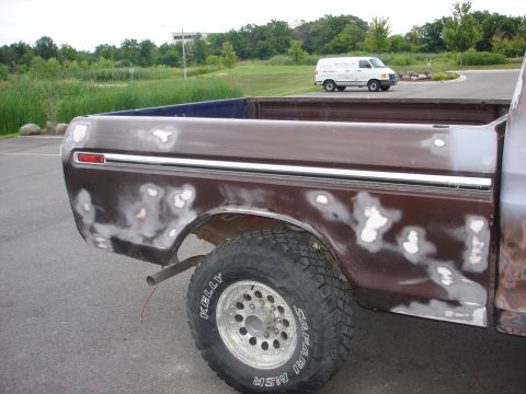 1979 Ford F-250 - This 1979 Ford F-250 pickup truck bed shows extensive body filler work. A white van is visible in the background.