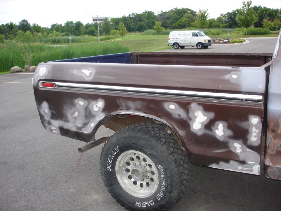 1979 Ford F-250 bed side with body filler patches. White van in background