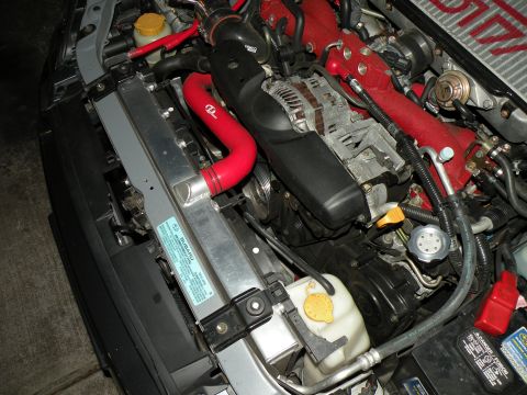 1998 Subaru Legacy - Close-up of a Subaru engine bay, red hoses and a silver radiator with visible branding.