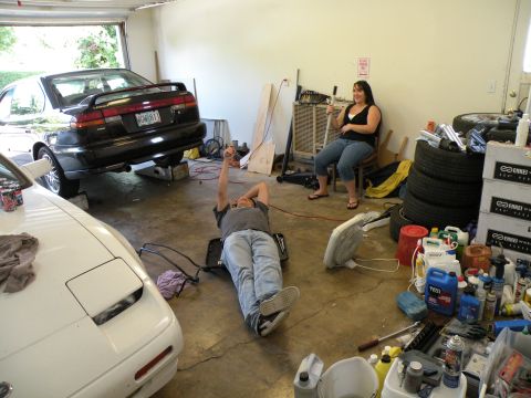 1998 Subaru Legacy - A black 1998 Subaru Legacy sedan is parked in a garage, elevated on ramps for maintenance.