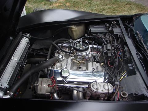 Black 1975 Chevrolet Corvette engine bay with chrome accents and a large carburetor
