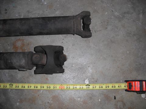 1991 Ford Bronco - Two driveshafts are shown with a tape measure indicating their lengths, with the longer shaft above the shorter one.