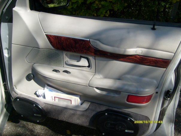 driver's side door panel with wood trim, power window controls, and a speaker