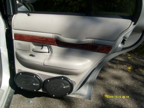 2000 Mercury Grand Marquis - The interior of a 2000 Mercury Grand Marquis shows a light-colored door panel with wood accents and aftermarket speakers.
