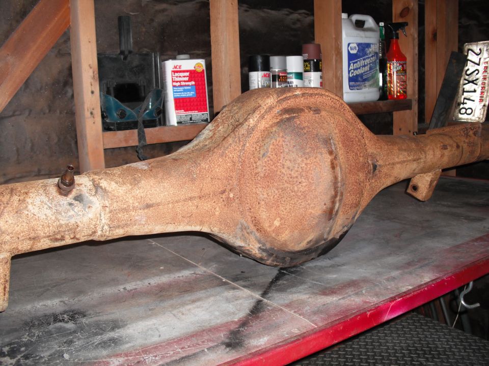 Rusty rear axle housing with differential on a garage workbench