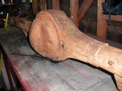 1991 Ford Bronco - A heavily rusted rear axle assembly is shown resting on a metal workbench in a garage or workshop setting.